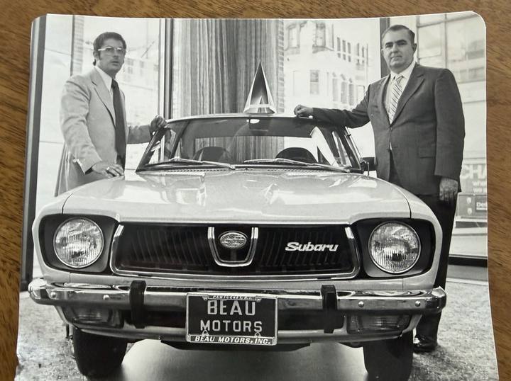 Two men beside a new Subaru in the Beau Motors showroom, Pawtucket, Rhode Island